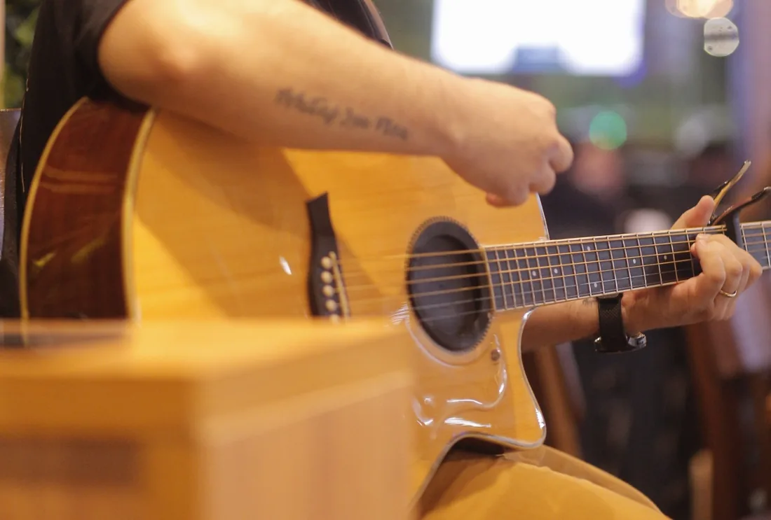 Manos de ToN tocando guitarra acústica en un show en vivo en Asunción